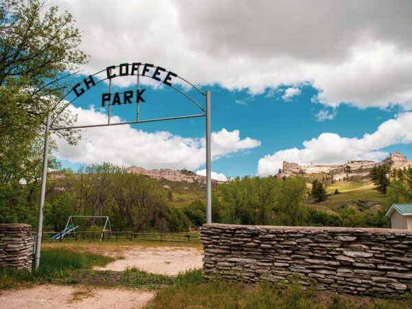 Gate and stone fence at Coffee Park entrance with buttes in the background