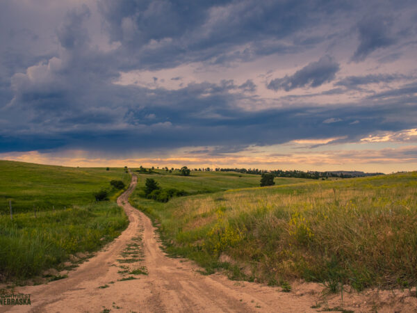 Country road through the prairie with stormy sky