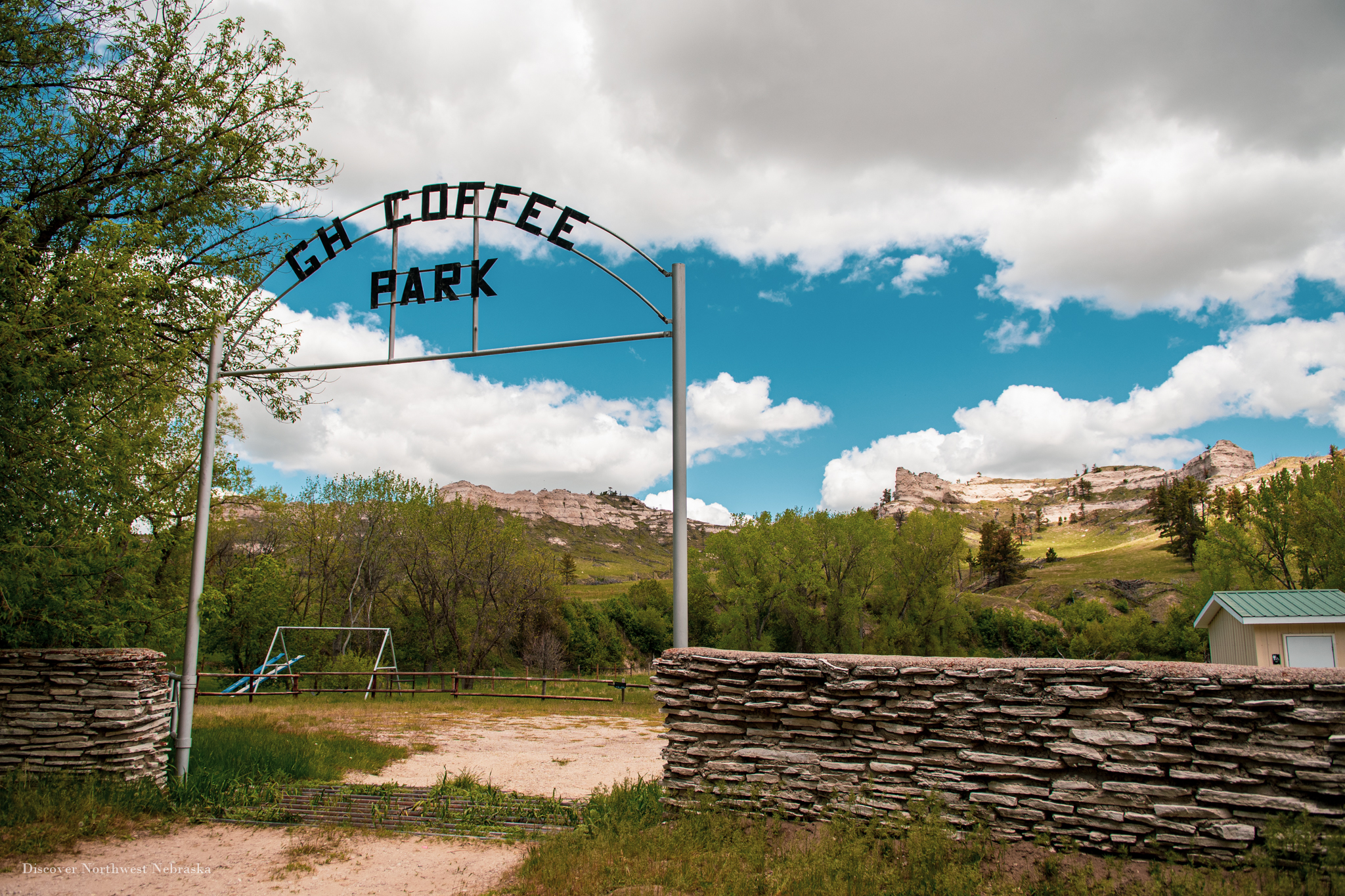 Gate and stone fence at Coffee Park entrance with buttes in the background