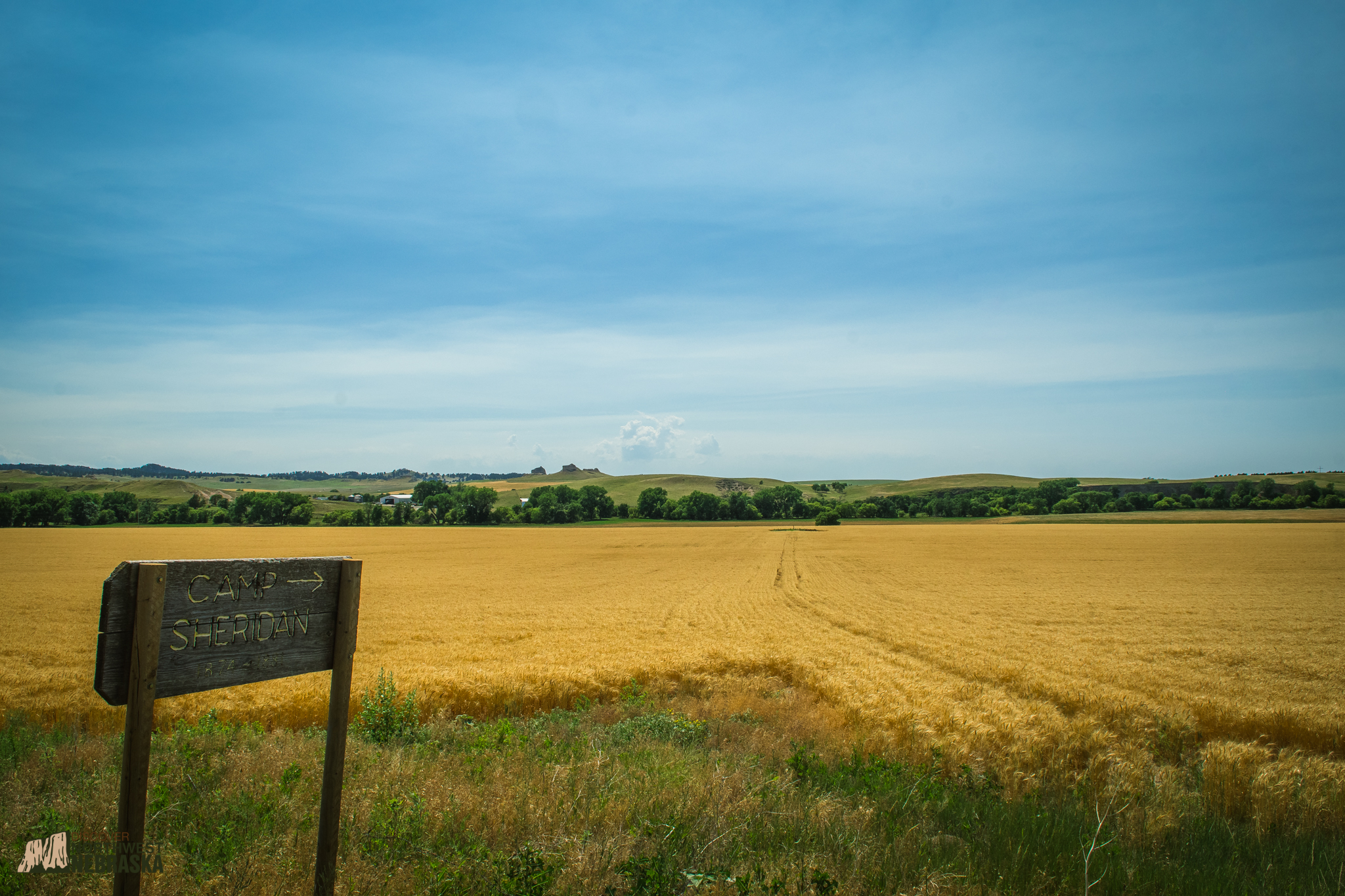 Camp Sheridan wooden sign with wheat field