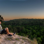 Man sitting on scenic overlook viewing pine trees at The Cliffs
