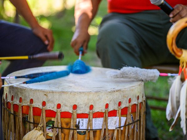 A Native American drum rests in the center of a circle of men.
