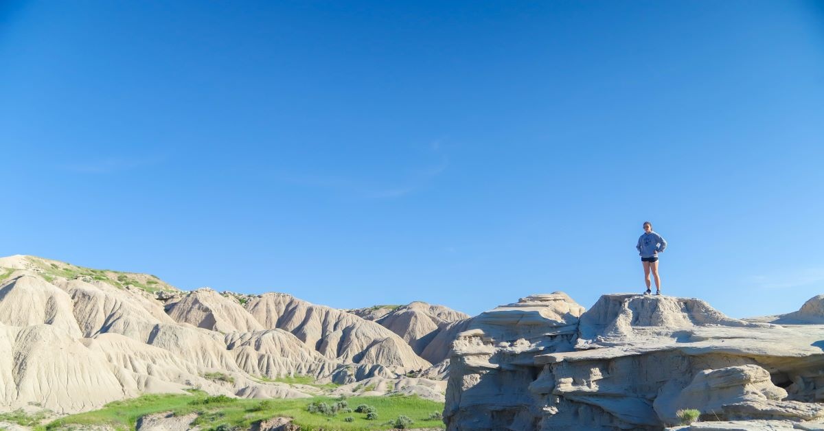 A girl stands on top of a rock.